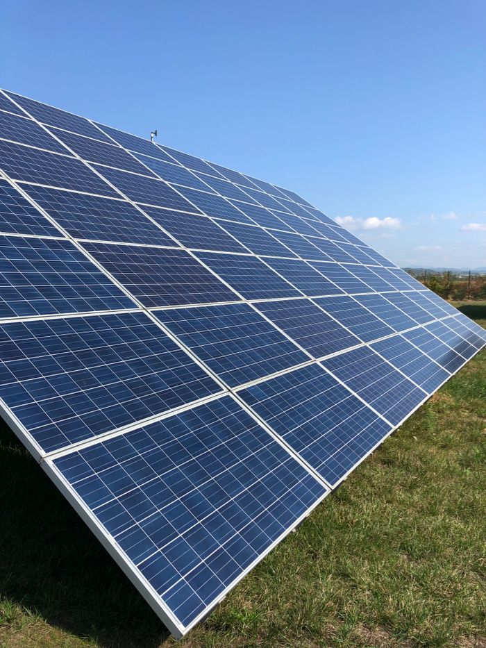 Kezdőlap Solar panels in a green field on a sunny day, showcasing renewable energy in Tortona, Italy.
